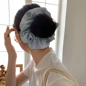 Blue satin scrunchie with pearls and silver heart charms shown on a model's ponytail