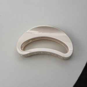 Detail view of cream-white matte hair claw clip with minimalist hollow moon shape design