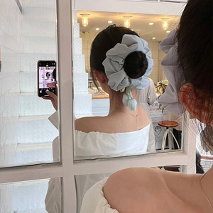 Elegant oversized light blue scrunchie with 3D tulip charms worn on a bun hairstyle