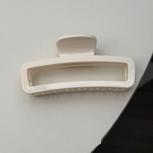 Top view of a creamy white rectangular hollow hair claw clip with smooth resin finish