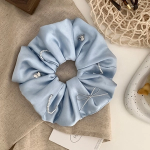Blue satin scrunchie with pearls, silver bear charm, and heart pendant for high-end bun styles