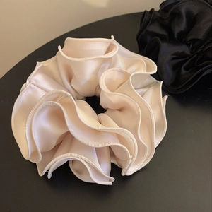 Detail showing layers of ivory and black satin scrunchies with pleated ruffle edges