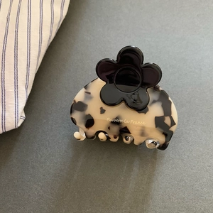 Detailed macro of tortoiseshell hair claw with black floral accent and golden logo