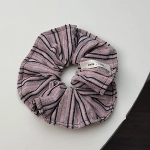 Roze en zwart gestreepte scrunchie met gebreide textuur en een wit geweven label