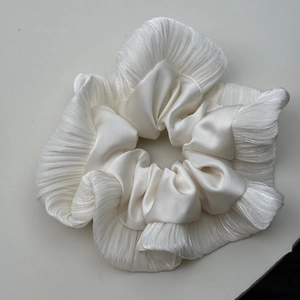 Détail d'un chouchou en satin blanc avec des bords à volants élégants et une texture brillante