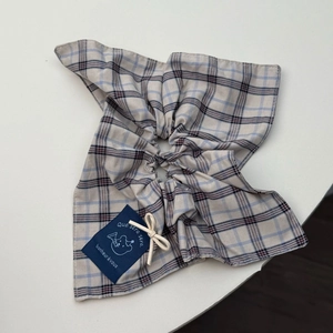 Detail eines blau gestreiften Haargummis mit süßem Bären-Webetikett und Stofftextur
