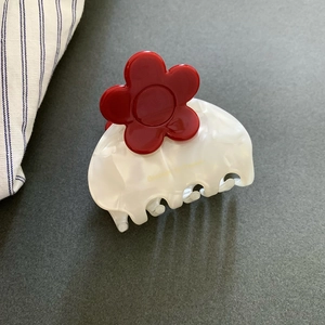 Detail of red floral hair claw clip with white marble pattern and Sweet Love text