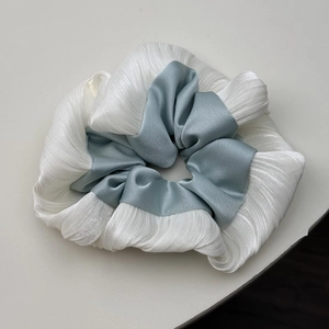 Détail des textures en satin bleu et tissu plissé blanc sur un chouchou de style ballet