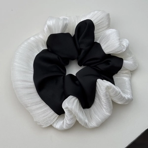 Vue détaillée du chouchou à volants noir et blanc avec textures de tissus superposés