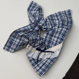 Détail du chouchou à carreaux bleus avec bordure en dentelle et nœud en ruban marine