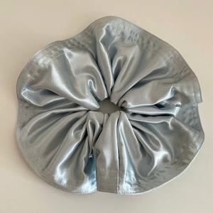 Gros plan d'un chouchou élégant en satin bleu argenté avec coutures et tissu plissé