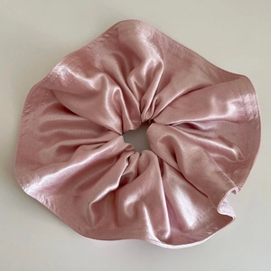 Détail d'un chouchou élégant en satin rose montrant la texture soyeuse et les plis