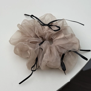 Détail d'un chouchou en organza champagne orné de multiples nœuds en ruban noir