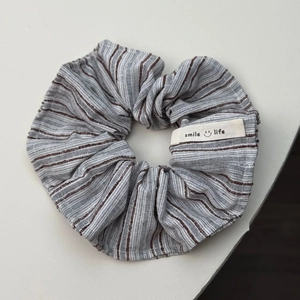 Detailopname van de grijs en bruin gestreepte haarelastiek met Smile Life stoffen label