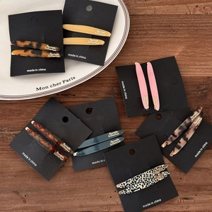 Elegant tortoiseshell and acetate barrette set displayed on a rustic wood background