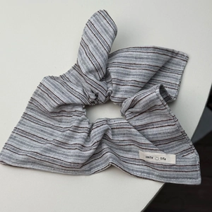 Detail van gestreepte stoffen scrunchie met strik en Smile Life-label op katoen-linnen materiaal