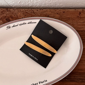 Close-up of amber acetate hair clips with Barrette La France engraving on a ceramic plate