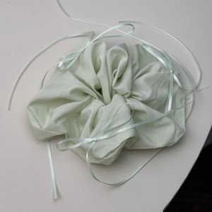 Detail view of mint green fabric hair scrunchie featuring elegant ribbon bow accents