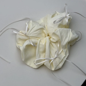 Close-up of cream scrunchie with white ribbon bow and soft cotton fabric detail