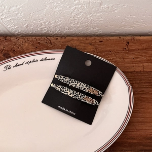 Macro detail of two elegant leopard print acetate hair clips on a premium display card