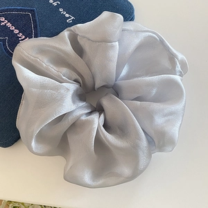 Detailed view of the silver grey silk satin scrunchie with soft pleated texture