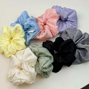 Set of 8 pleated scrunchies in pastel colors with handmade labels on white background