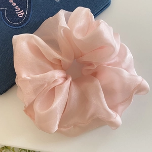 Close-up of pink mesh fabric scrunchie with soft pleats on a blue denim background