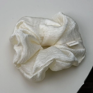 Detail view of cream white textured fabric scrunchie featuring a Hand Made woven label