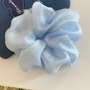 Close-up of light blue mesh scrunchie with satin texture and elegant pleated details