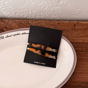 Detail view of a pair of tortoiseshell acetate hair clips on a black card display