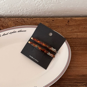 Elegant tortoise shell pattern acetate hair clip set on minimalist white ceramic plate