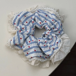 Macro detail of striped scrunchie with red hearts, cream lace trim and white pearls