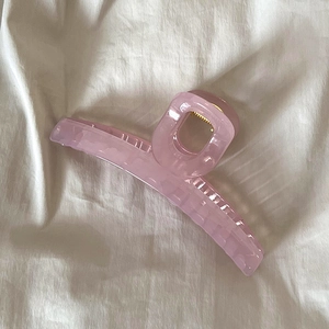 Vue détaillée d'une grande pince à cheveux rose en résine sur un tissu blanc doux