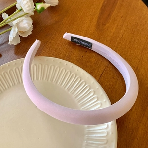 Détail d'un serre-tête rembourré en tissu rose clair avec une étiquette noire faite à la main