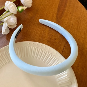 Détail du serre-tête rembourré bleu clair avec étiquette faite main sur céramique