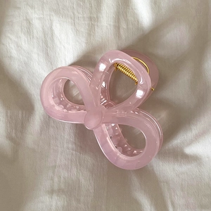 Détail de la pince à cheveux en résine rose avec nœud papillon sur tissu en lin