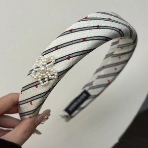 Detail of sponge headband featuring red hearts, black stripes and pearl flower applique