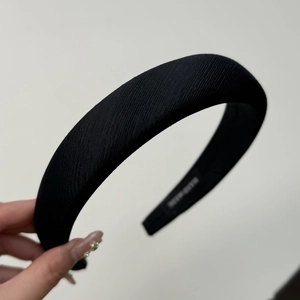 Macro detail of handmade black fabric headband with sponge padding and white woven label