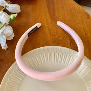 Détail d'un serre-tête en satin rose rembourré avec étiquette textile faite à la main