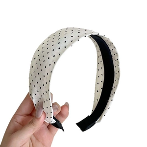 Cerchietto largo bianco a pois neri classici mostrato in uno scatto in studio