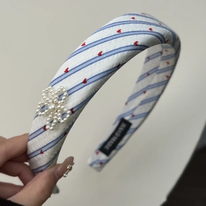 Close-up of heart striped headband with a detailed handmade pearl bow accessory