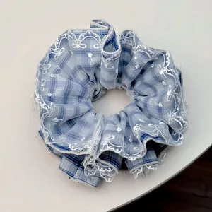 Elegant blue and white plaid scrunchie with delicate lace embroidery trim for hair styling