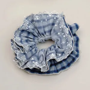 Detail of blue plaid scrunchie with white lace embroidery for elegant hair styling