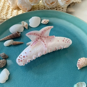 Dettaglio della pinza per capelli a stella marina in acetato rosa con strass lucidi