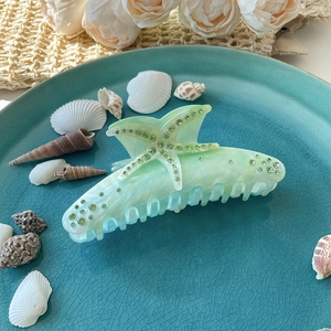 Dettaglio della molletta a stella marina con strass verdi su vassoio in ceramica