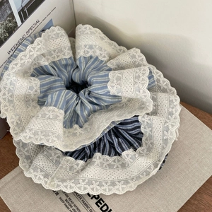 Two blue striped lace scrunchies on a textured board for elegant ponytail styling