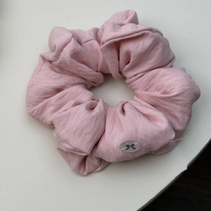 Nahaufnahme von rosa Puff-Haargummi mit einer Kunststoff-Schnalle und Schleifenmuster