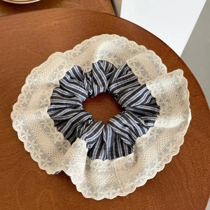 Blue striped scrunchie with ivory lace trim on a rustic wooden table top