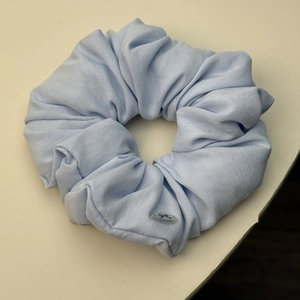 Detailansicht eines hellblauen Scrunchie aus weichem Stoff mit kleinem Schleifendekor
