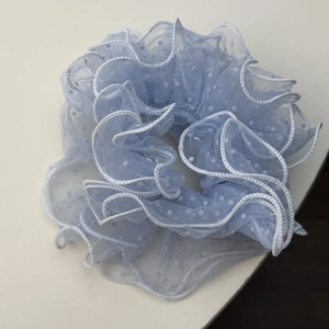 Detail of light blue mesh scrunchie with white polka dots and elegant ruffled edges